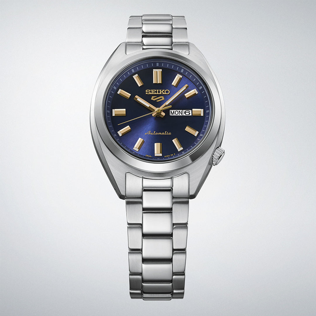 Seiko 5 Sports SRE021K1 navy dial automatic watch displayed upright on gradient grey background, showing full case and bracelet profile