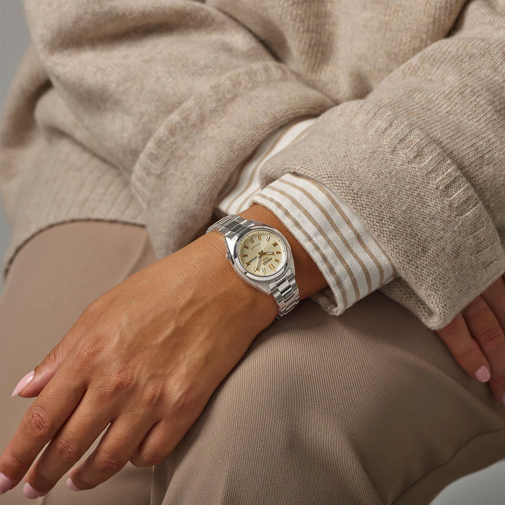 Seiko 5 Sports SRE023K1 cream dial automatic watch worn on wrist, styled with a white button-down and cream cable-knit sweater