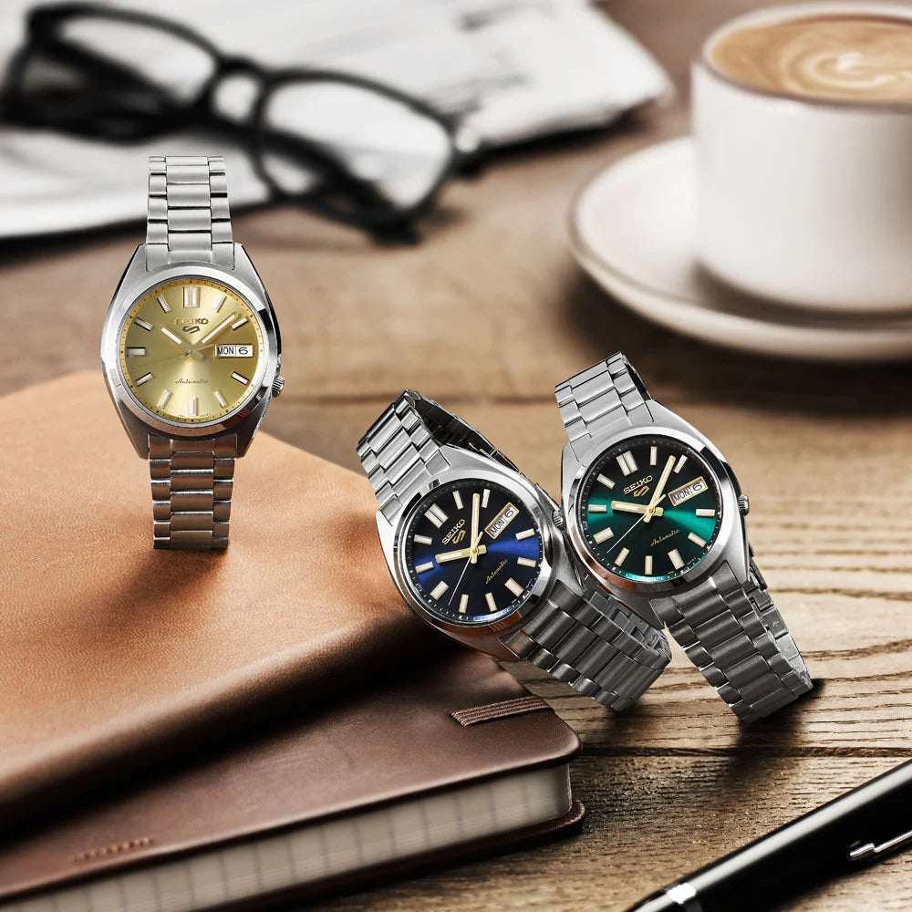 Seiko 5 Sports SNXS Series automatic watches — three colourways: champagne gold SRPL59K1, midnight blue SRPL57K1, and forest green SRPL55K1 with stainless steel bracelets
