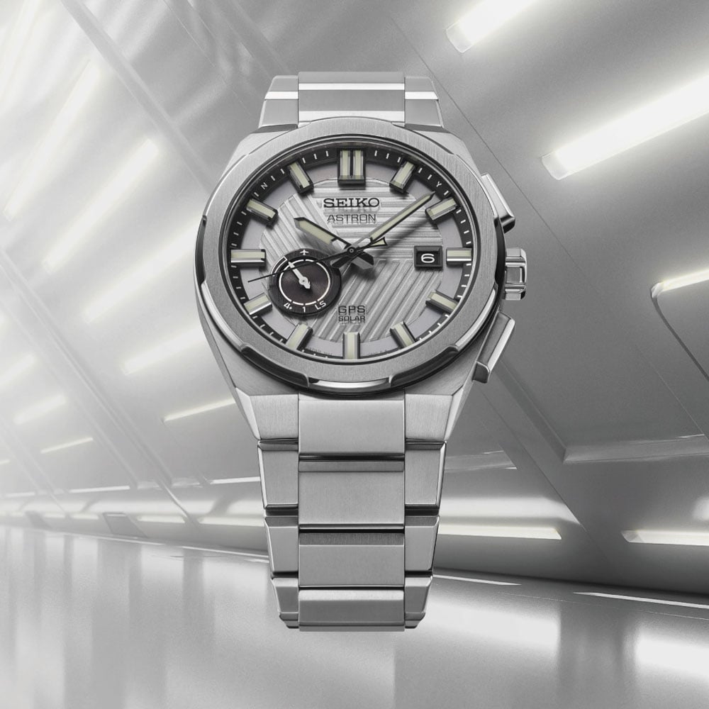 Seiko Astron SSJ037J1 GPS Solar 2025 Limited Edition watch displayed against a silver architectural corridor, highlighting the brushed stainless steel case and textured dial