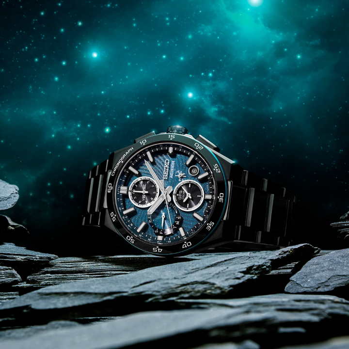 Seiko Astron SSH187J1 Spiral Galaxy GPS solar chronograph limited edition — dark turquoise blue textured dial with glittered star effect, all-black titanium case, styled on rocky terrain with starry night sky