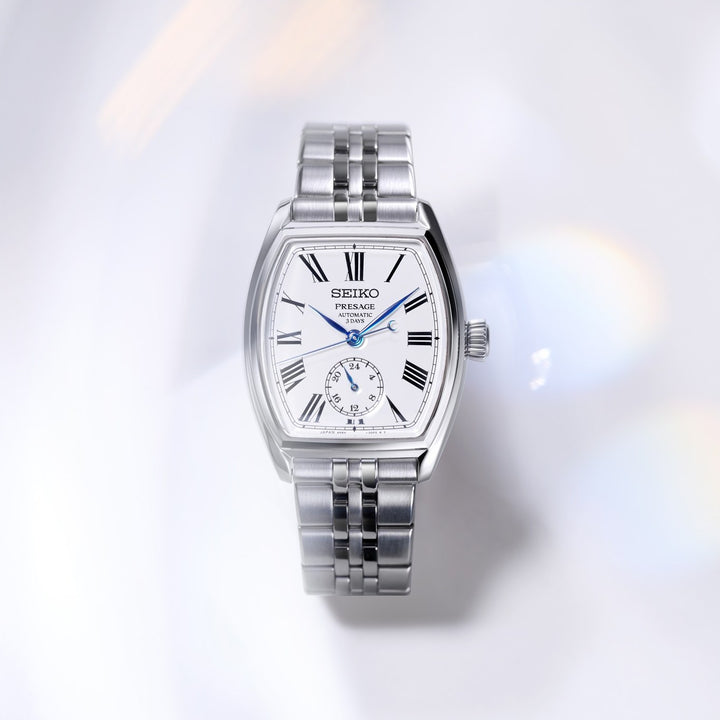 Seiko Presage SPB537J1 Classic Series tonneau automatic watch — white enamel dial with Roman numerals and blue hands, silver stainless steel bracelet, top-down lifestyle flat lay