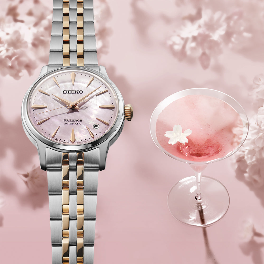 Seiko Presage SRPM06J1 Cocktail Time Sakura Aviation limited edition — pink mother-of-pearl dial with two-tone bracelet, styled alongside the Sakura Aviation cocktail with cherry blossom backdrop