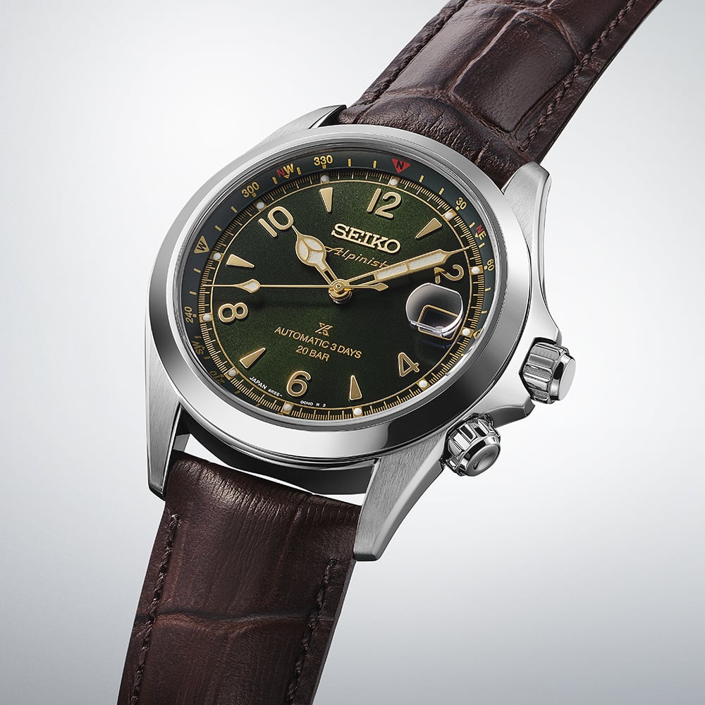 Seiko Prospex Alpinist SPB507J1 — angled three-quarter view on gradient grey background, showing the inner compass bezel, dual crown configuration, and dark brown cow leather strap