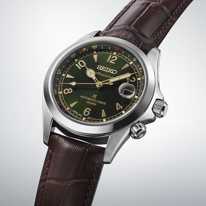 Seiko Prospex Alpinist SPB507J1 — angled three-quarter view on gradient grey background, showing the inner compass bezel, dual crown configuration, and dark brown cow leather strap