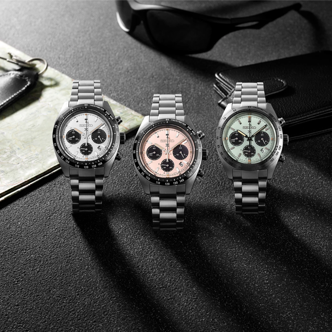 Seiko Prospex Speedtimer solar chronograph collection — white panda SSC961P1, pale pink SSC963P1, and mint green SSC965P1 with stainless steel bracelets, motorsport lifestyle shot