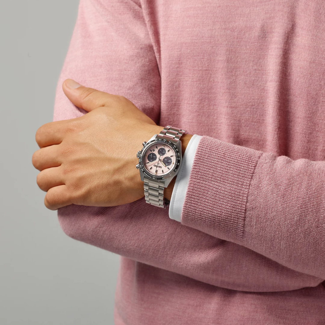 Seiko Prospex Speedtimer SSC963P1 solar chronograph worn on wrist — pale pink panda dial with black tachymetre bezel and stainless steel bracelet, styled with pink sweater
